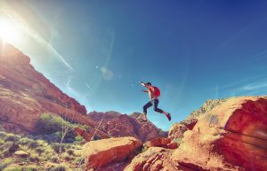 Man jumping across a rock on  ahiking trail