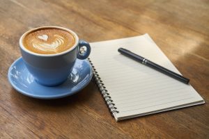 Coffee with notepad and pen next to it